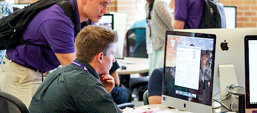 Students working together on a desktop computer in odegaard library